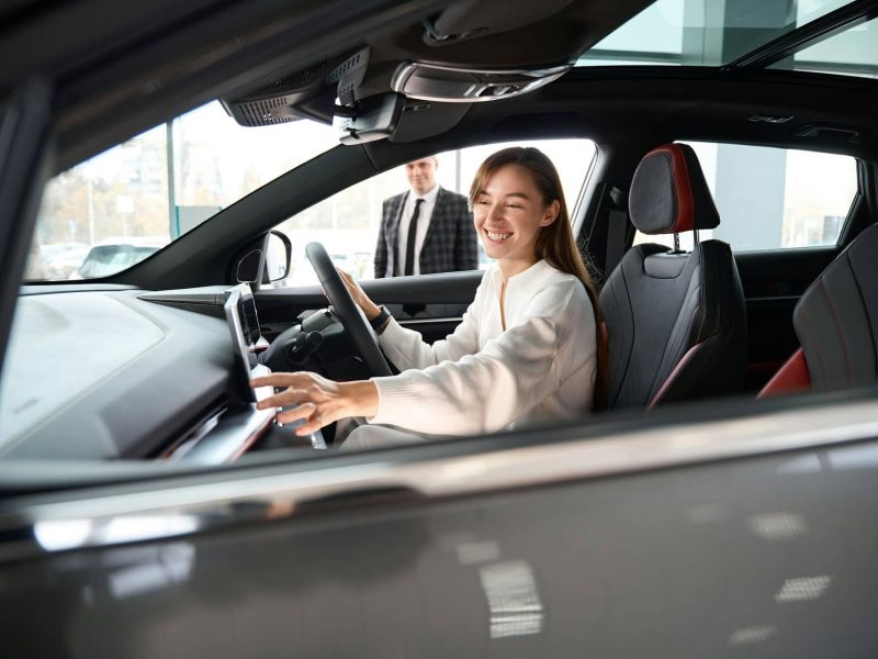 woman-choosing-new-car-in-dealership-with-salesman-trying-on-new-automobile.jpg